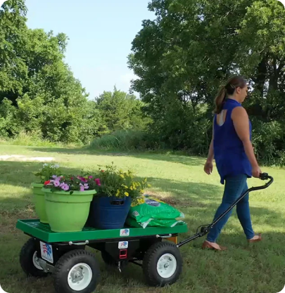 Woman hauling potted plants on green cart